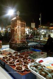 Image du Maroc Professionnelle de  Le samovar du vendeur de Khoudenjal, une infusion tonifiante constituée de plusieurs herbes aromatiques : elle réchauffe et ouvre l’appétit, aphrodisiaque se prend avant ou après repas. sur la place Djemaa El Fanaa plusieurs vendeurs de cette tisane et la proposent avec une sorte de farine cuite mélangées aux amandes, graines de sésames, cacao où , une atmosphère magique dans ces lieus au centre de la médina de Marrakech, le 1er Mars 2004. (Photo / Abdeljalil Bounhar)

